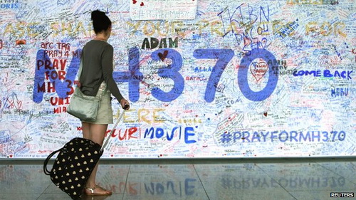 Một phụ nữ dừng lại trước tấm bảng ghi những lời cầu nguyện dành cho hành khách và phi hành đoàn trên chiếc MH370 ở sân bay Kuala Lumpur - Ảnh: Reuters
